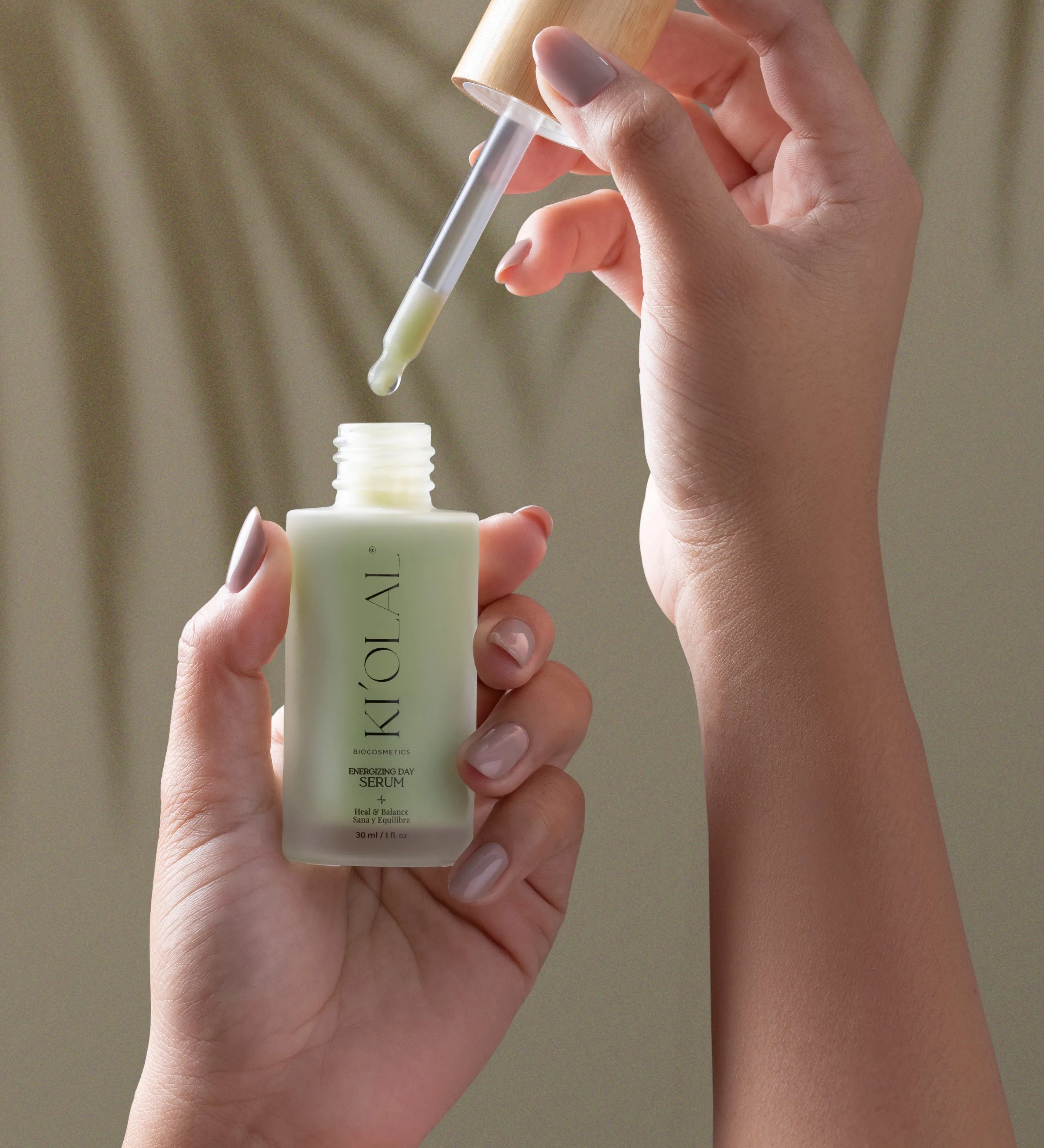 Hand holding KI'OLAL Day Serum bottle with dropper