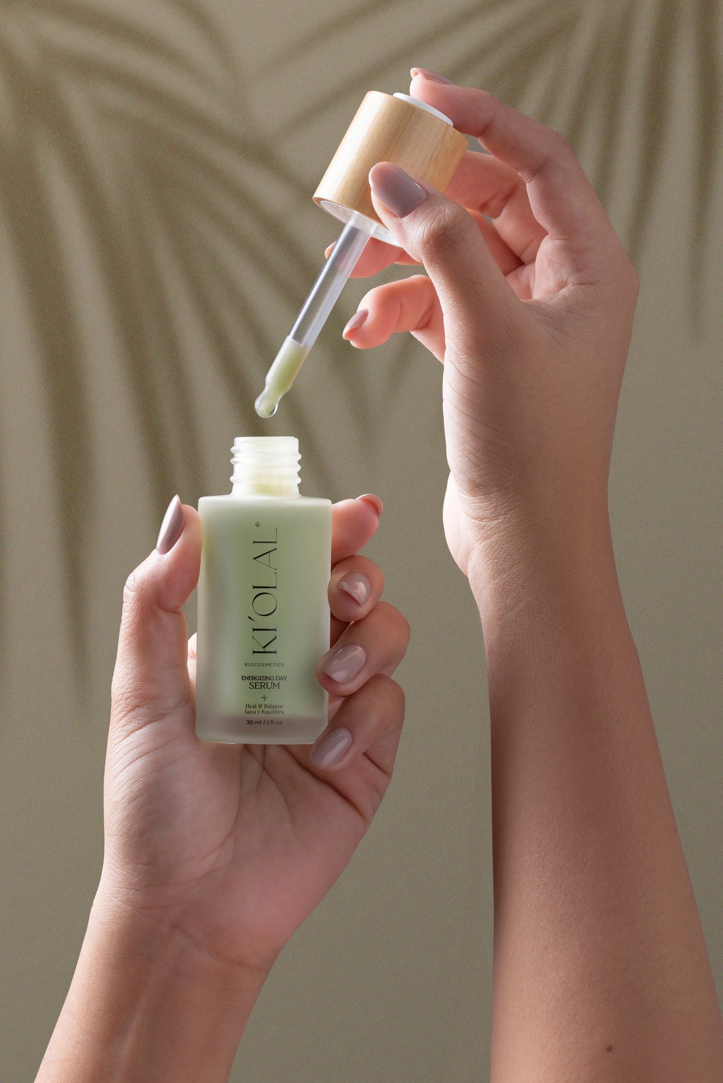 Hand holding KI'OLAL Day Serum bottle with dropper