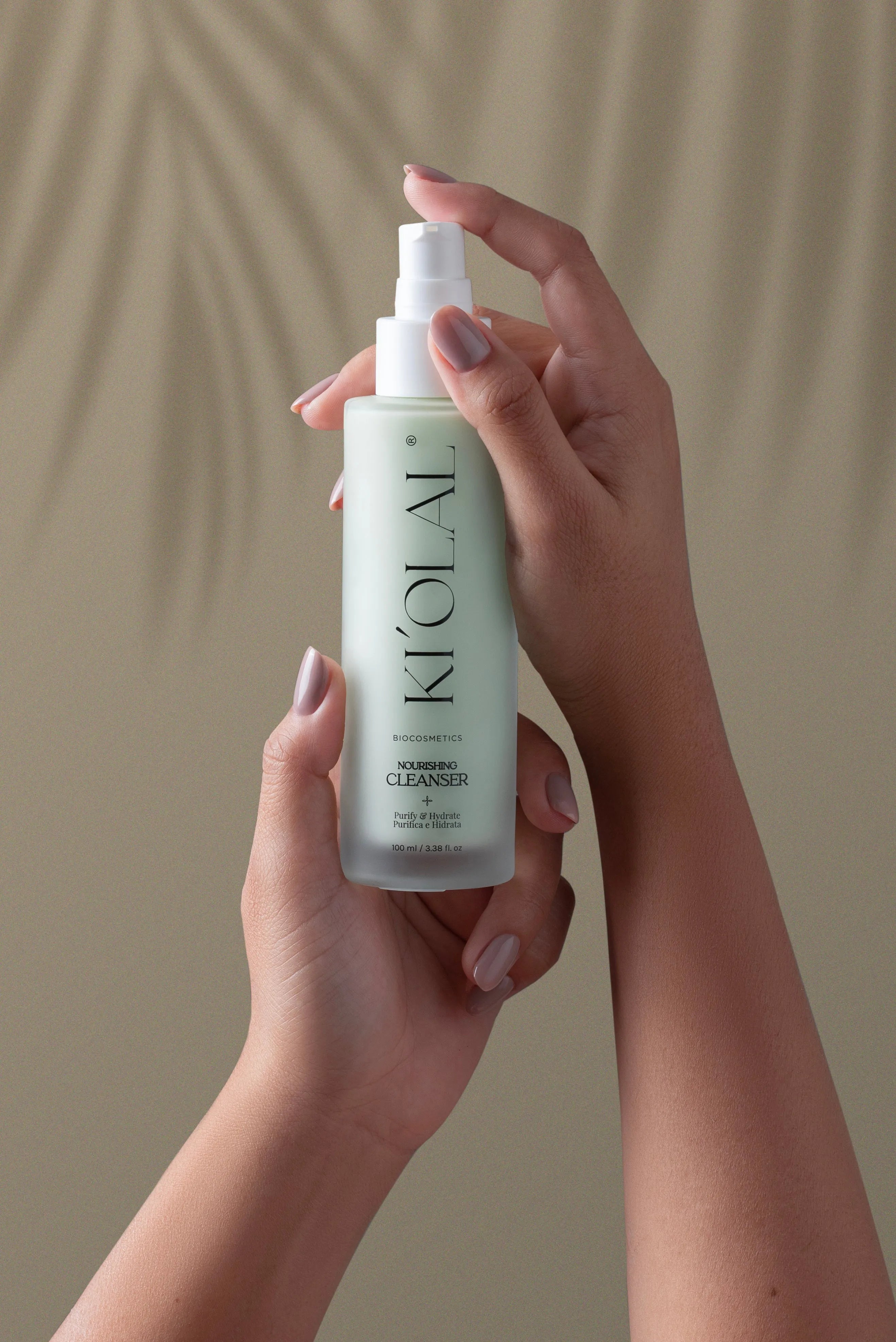 Hands holding KI'OLAL Cleanser bottle for daily skincare
