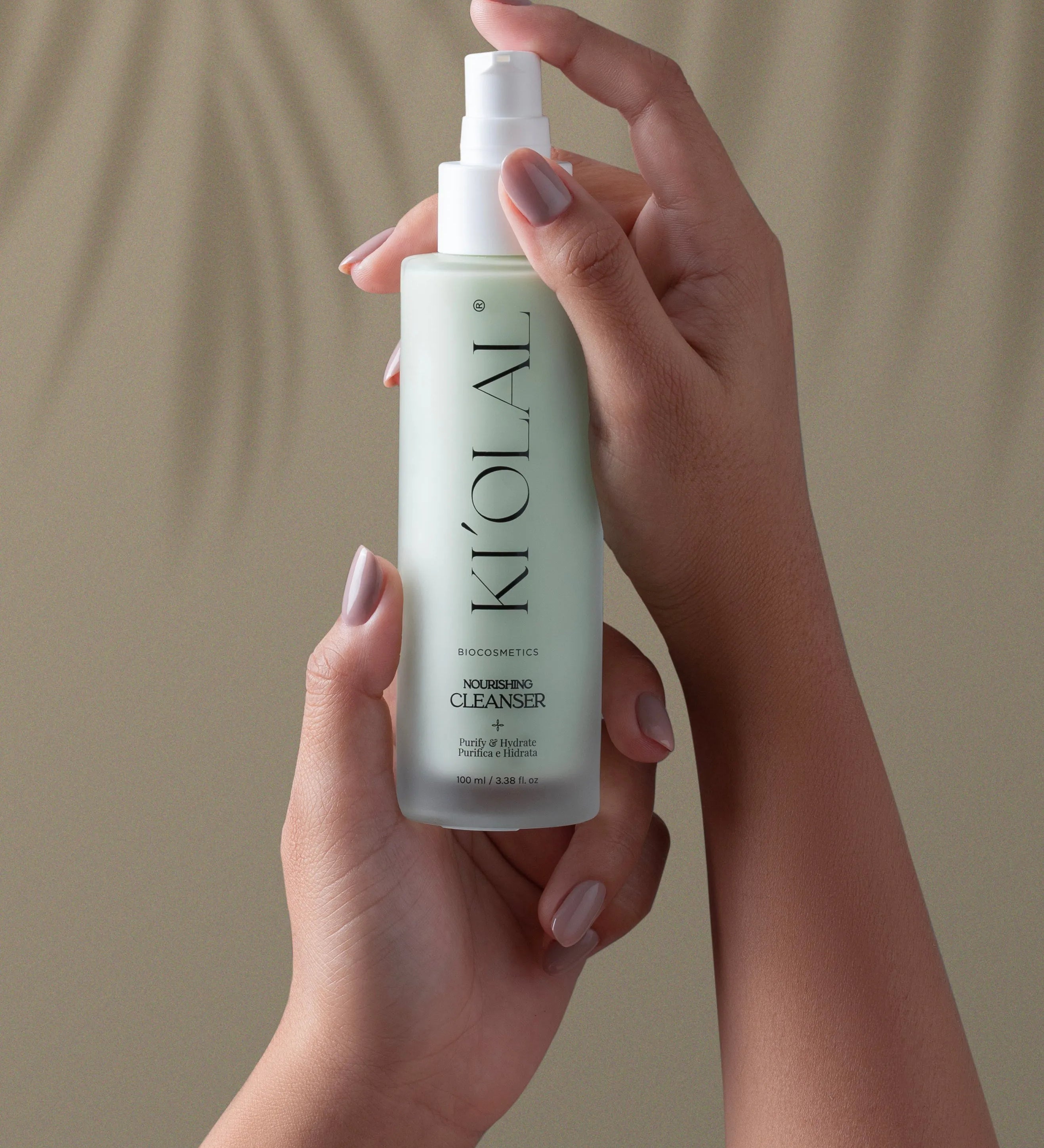 Hands holding KI'OLAL Cleanser bottle for daily skincare