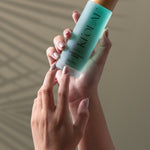 Hand holding KI'OLAL Mist with natural shadow backdrop