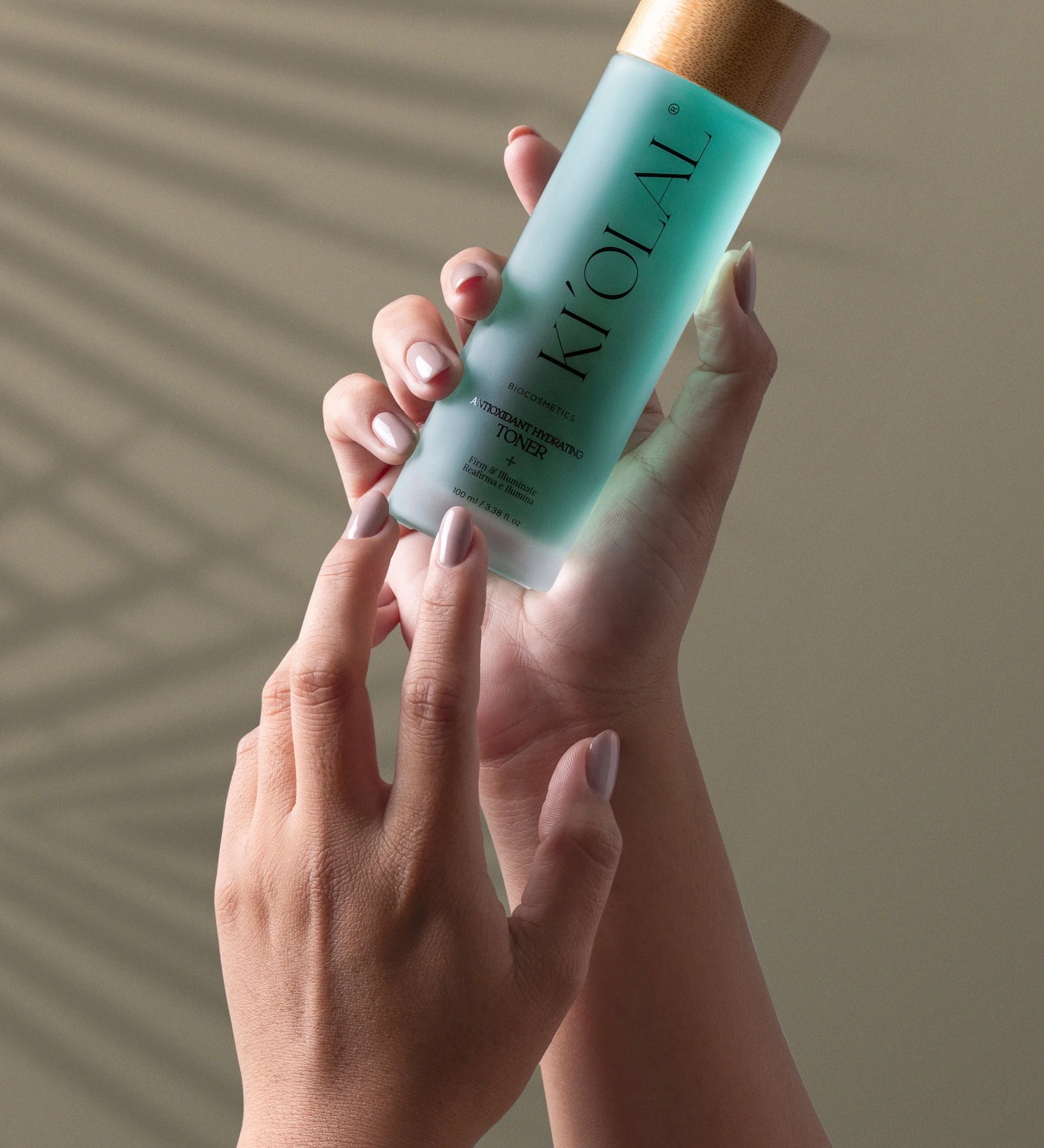 Hand holding KI'OLAL Mist with natural shadow backdrop