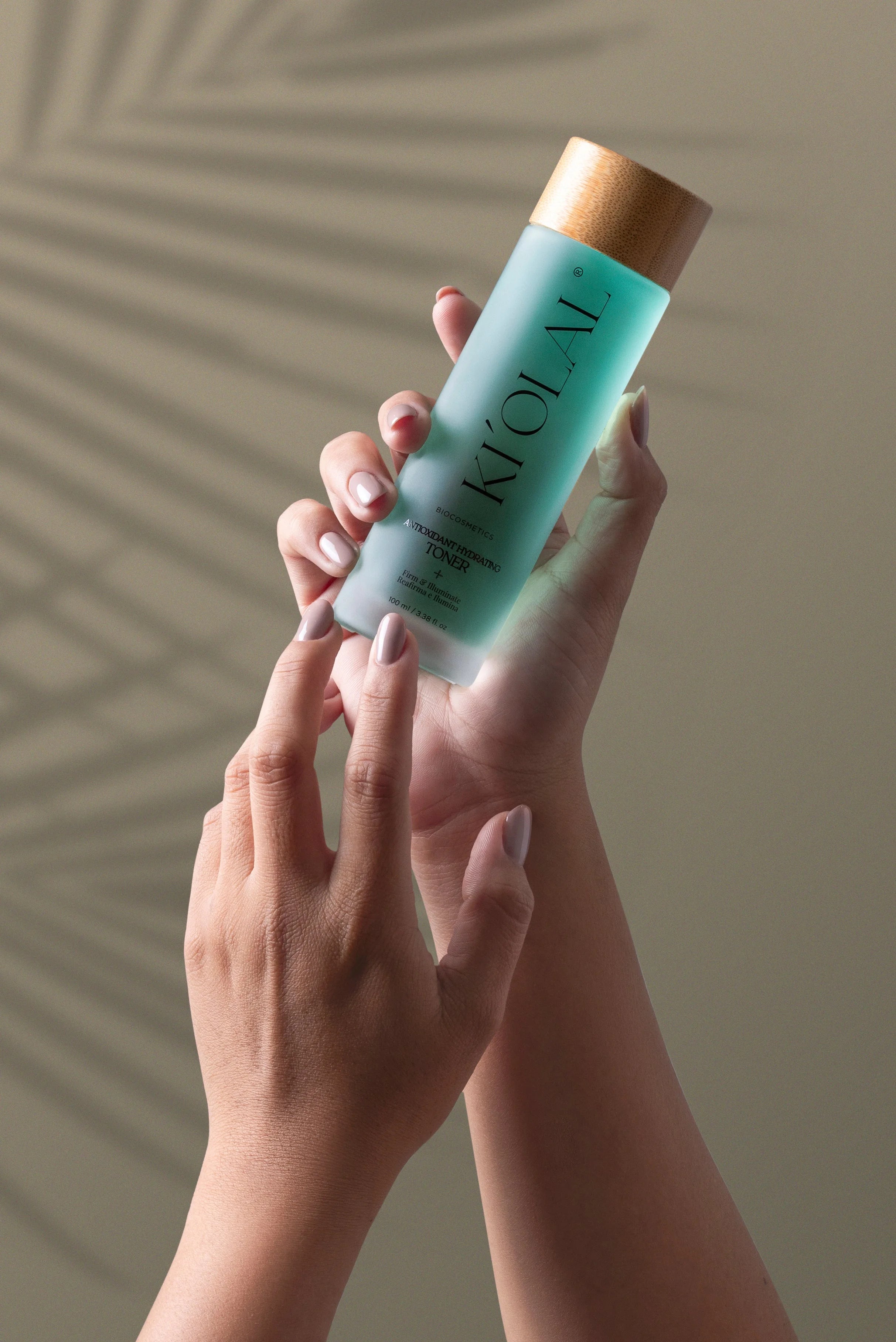 Hand holding KI'OLAL Mist with natural shadow backdrop